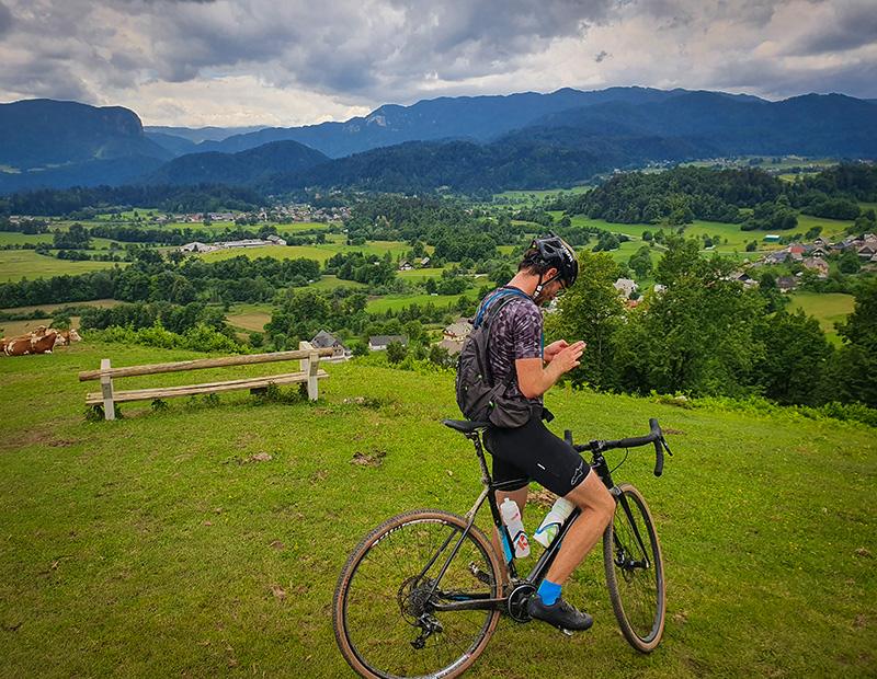 Cyclist taking a break on a meadow above Bled with panoramic views of Slovenia’s countryside.