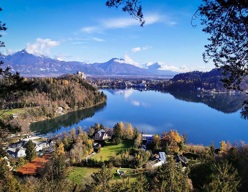 Panoramic view of Lake Bled in Slovenia with island church, castle and Julian Alps, highlight of cycling and walking holidays.