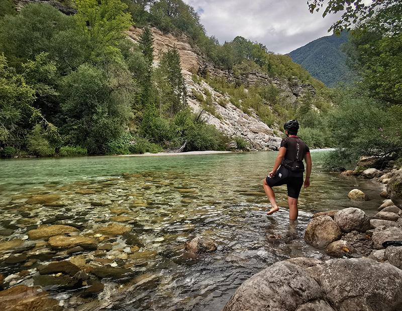 MTB rider standing in the clear waters of the Soča River in Slovenia, highlight of self-guided hiking holidays.