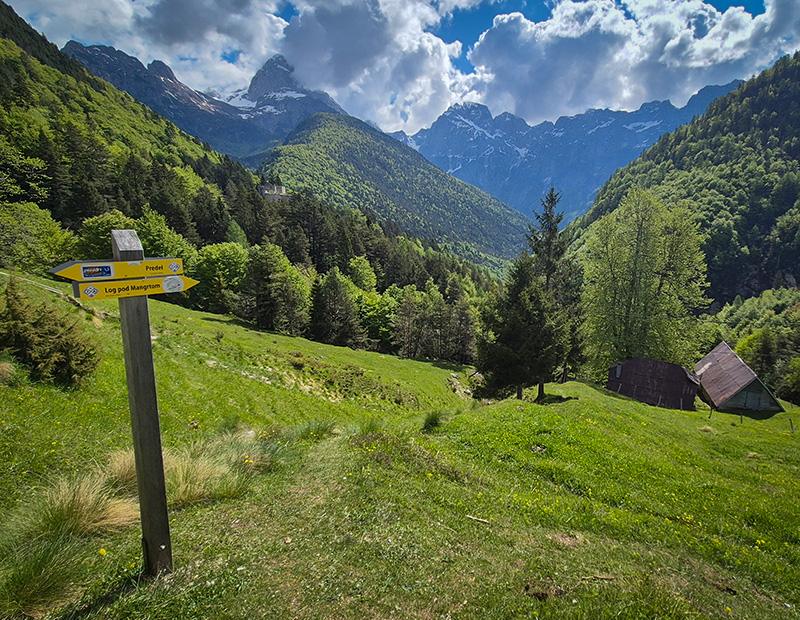 Alpine meadow with hiking trail signpost in Slovenia, gateway to self-guided trekking in Triglav National Park.