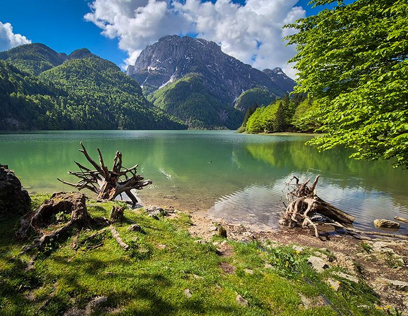 Lago del Predil near the Italian-Slovenian border, emerald alpine lake surrounded by mountains, part of Julian Alps hiking tours.