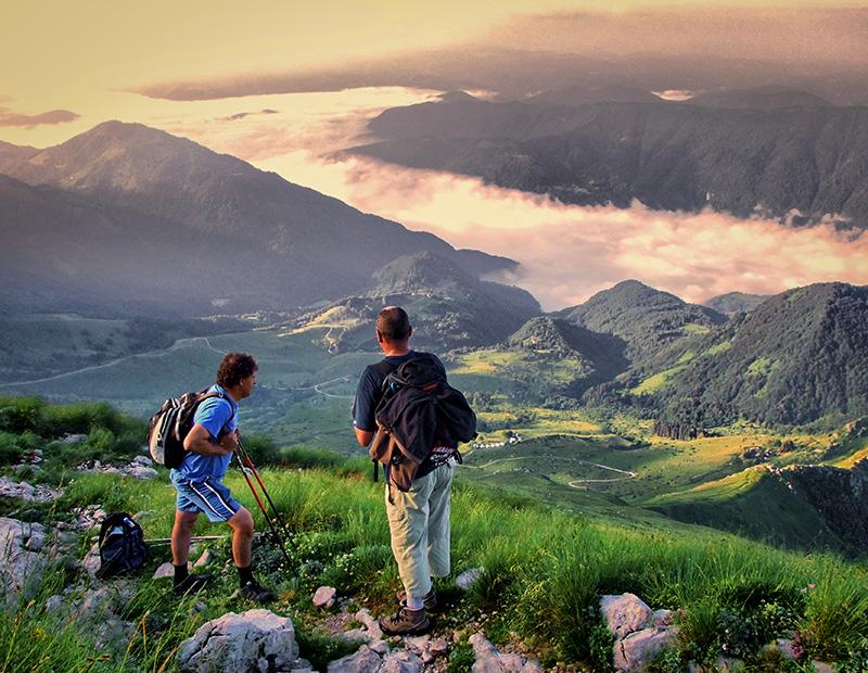 Father and son hikers enjoying sunset views over mountain valleys in Slovenia during a self-guided hiking holiday.
