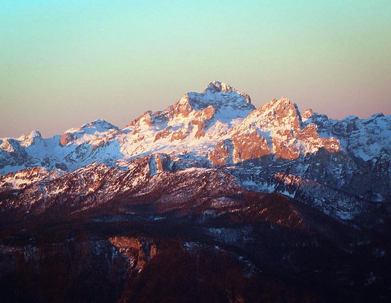 Sunset view over snow-covered peaks of the Julian Alps in Slovenia, highlight of trekking and hiking holidays.