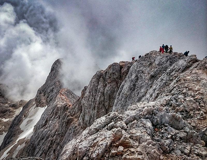 Hikers on the rocky summit of Mount Triglav, Slovenia’s highest peak, during a self-guided trekking holiday in the Julian Alps.